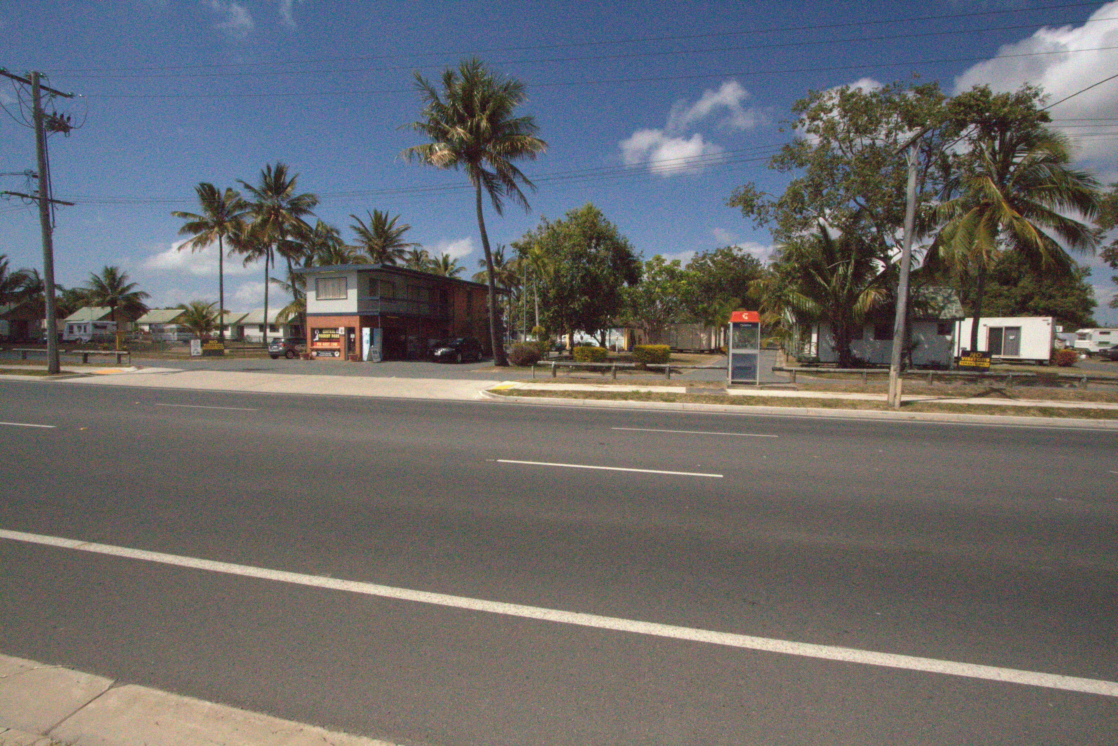 Una calle con una parada de autobús y palmeras.