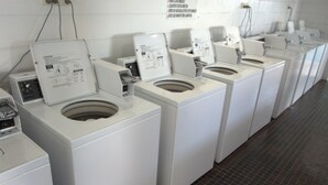 A row of white front-loading washing machines in a public laundromat with tiled floors. - Central Tourist Park (North Mackay)
