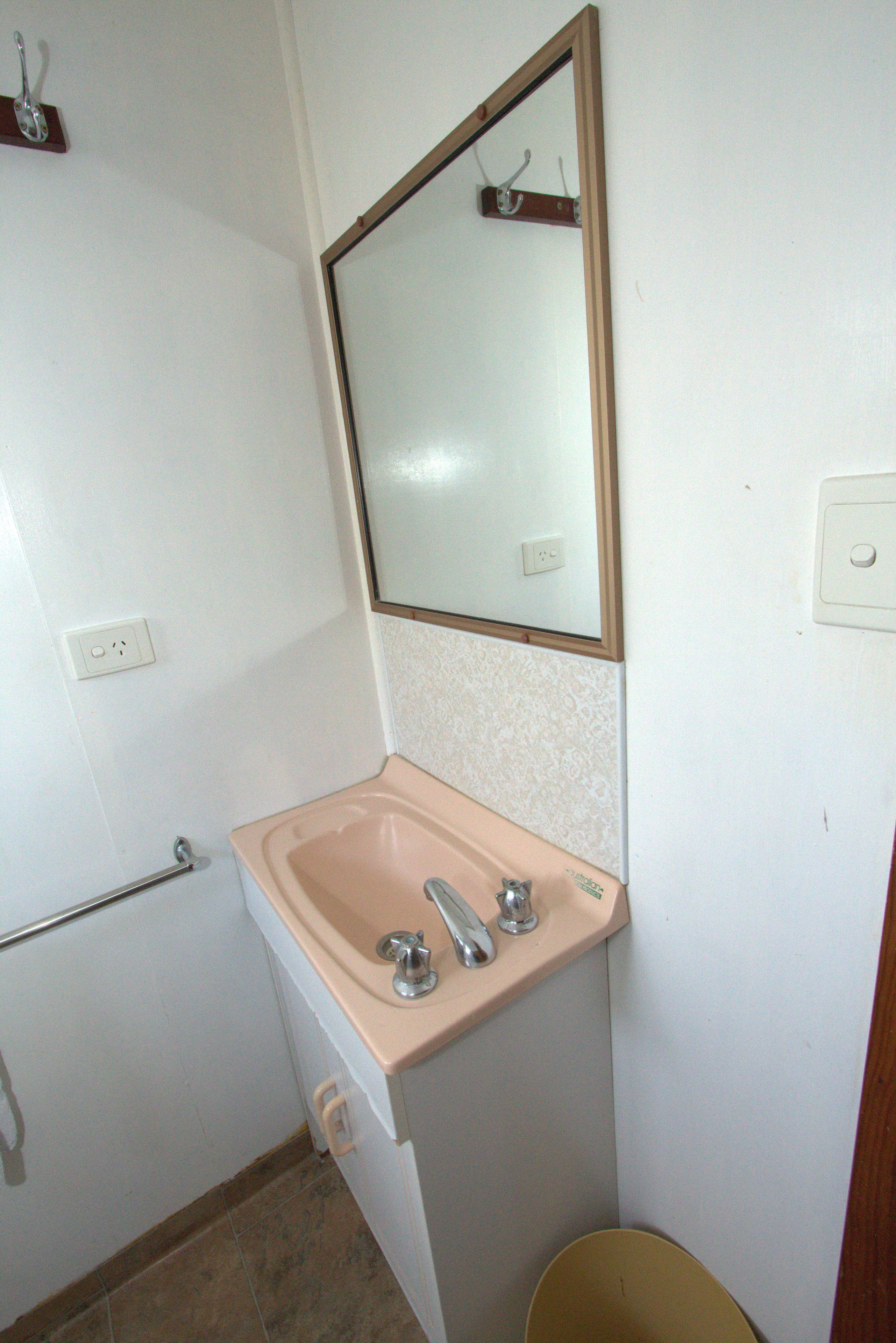 Un baño pequeño con lavamanos, espejo e inodoro.
