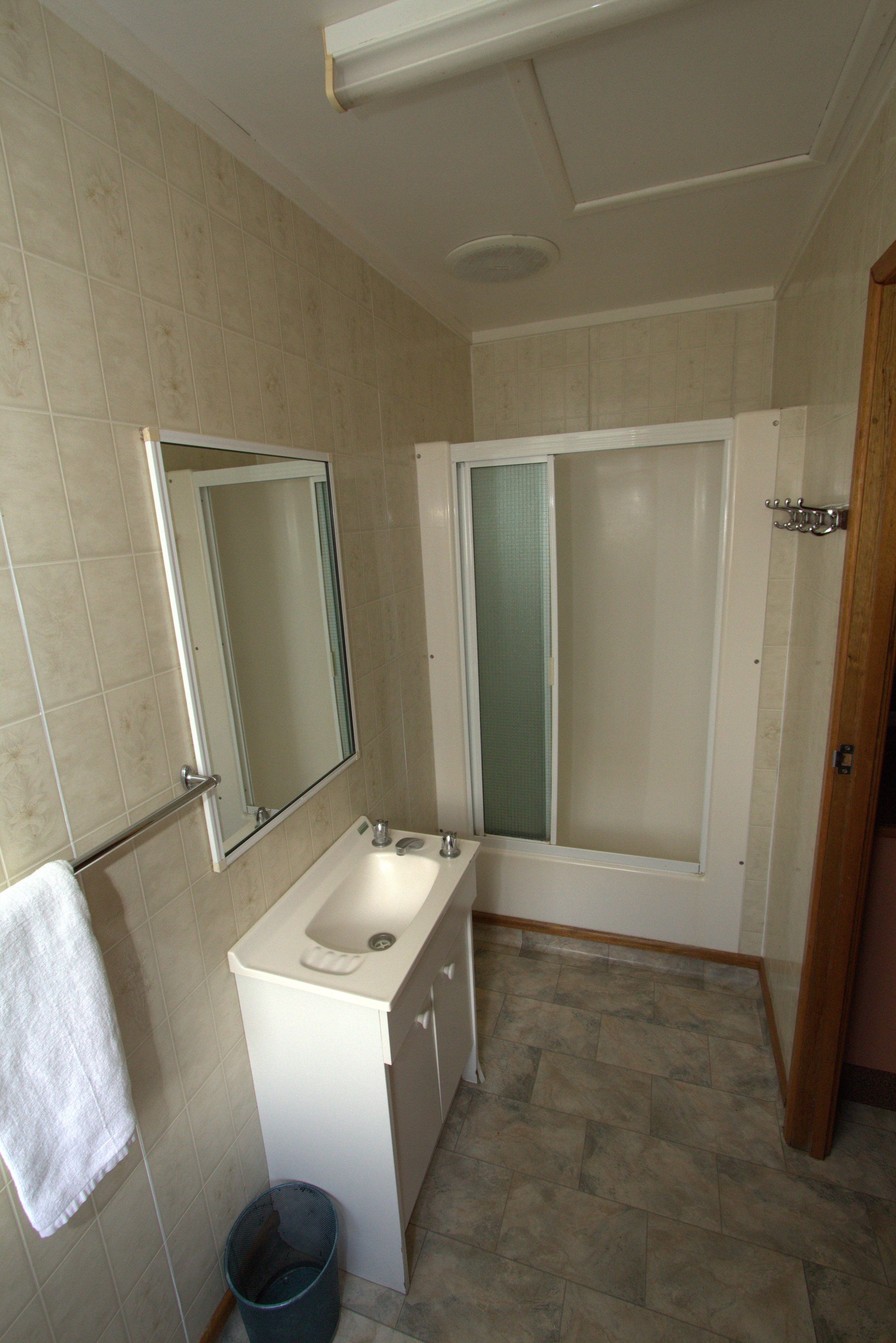 Un baño con lavamanos, espejo y ducha.