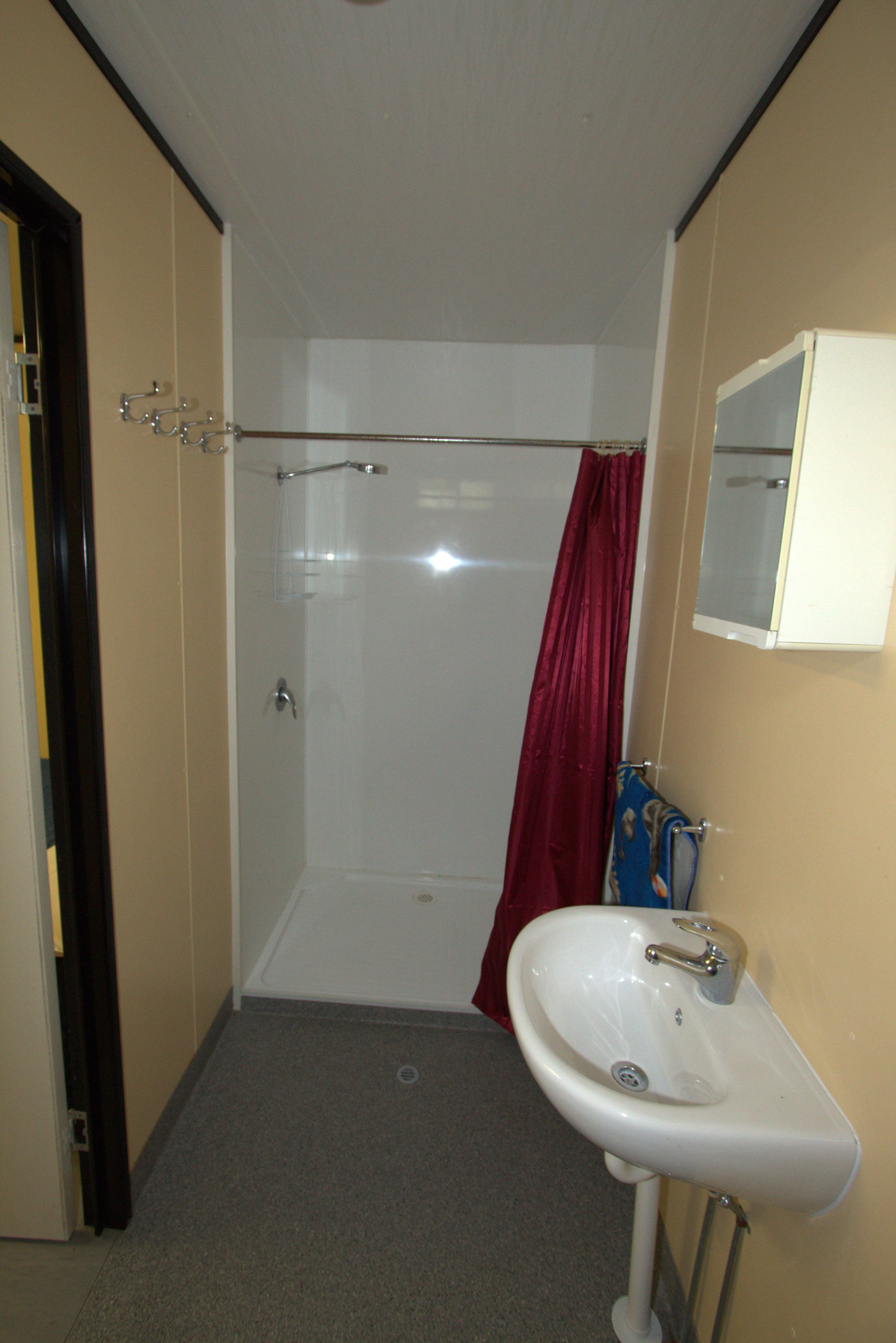 A bathroom with a shower, a sink, and a mirror.