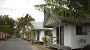 A row of single-story, white buildings with green roofs, numbered 19, along a paved street. - Central Tourist Park (North Mackay)