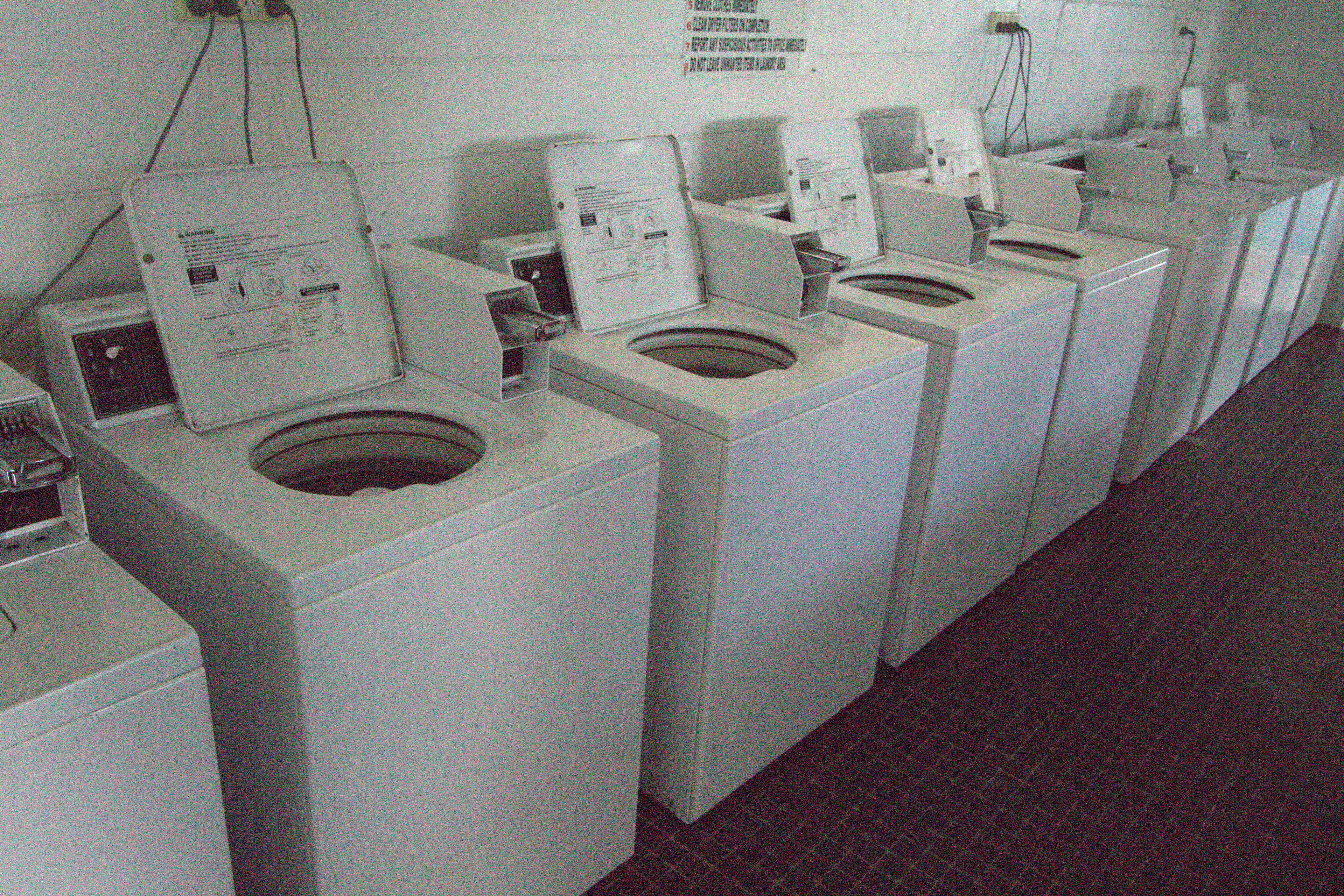 A row of front-loading washers and dryers in a public laundry facility.