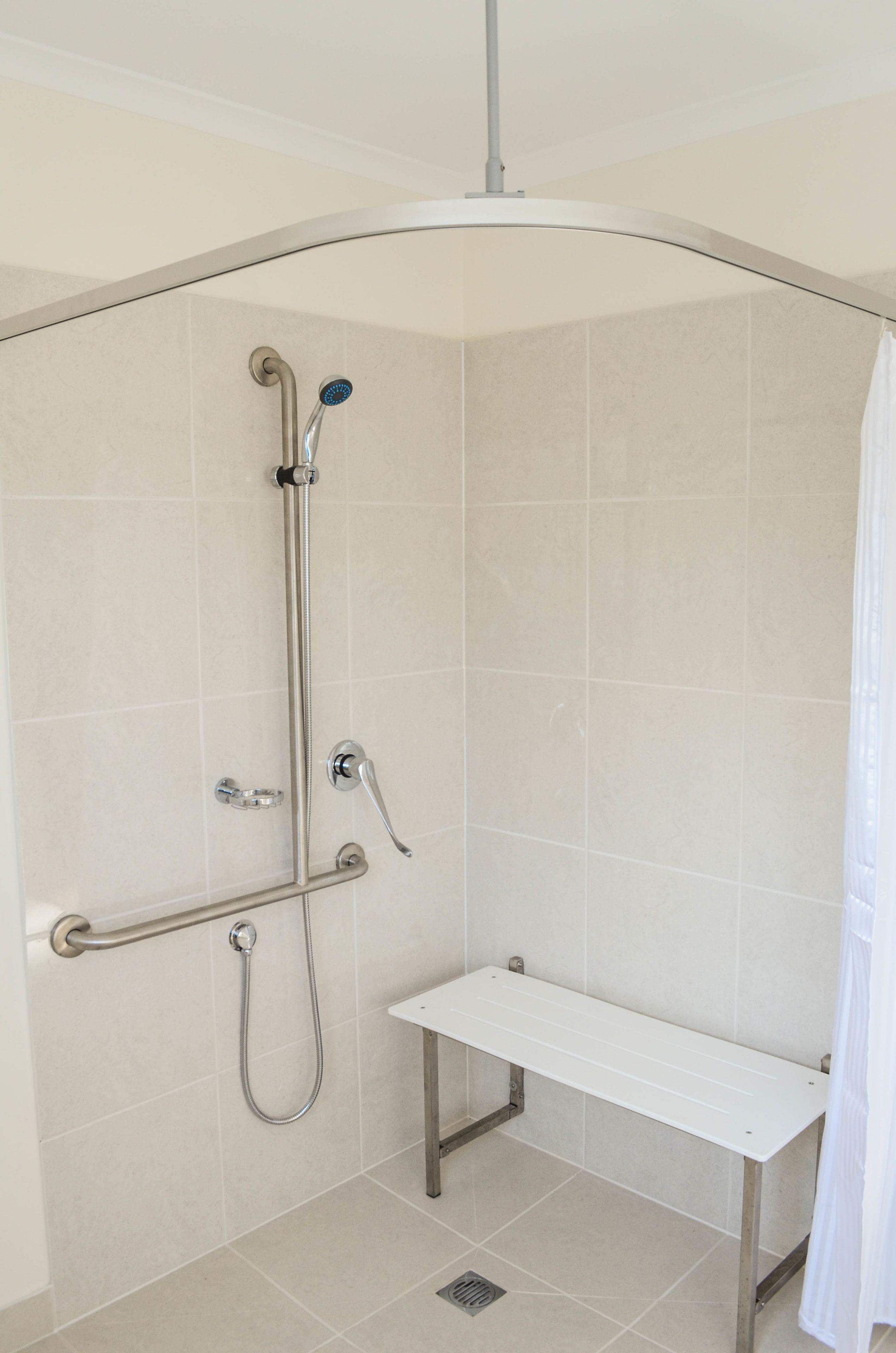 Een douche met een handdouche, een doucheaanslag en een bankje.