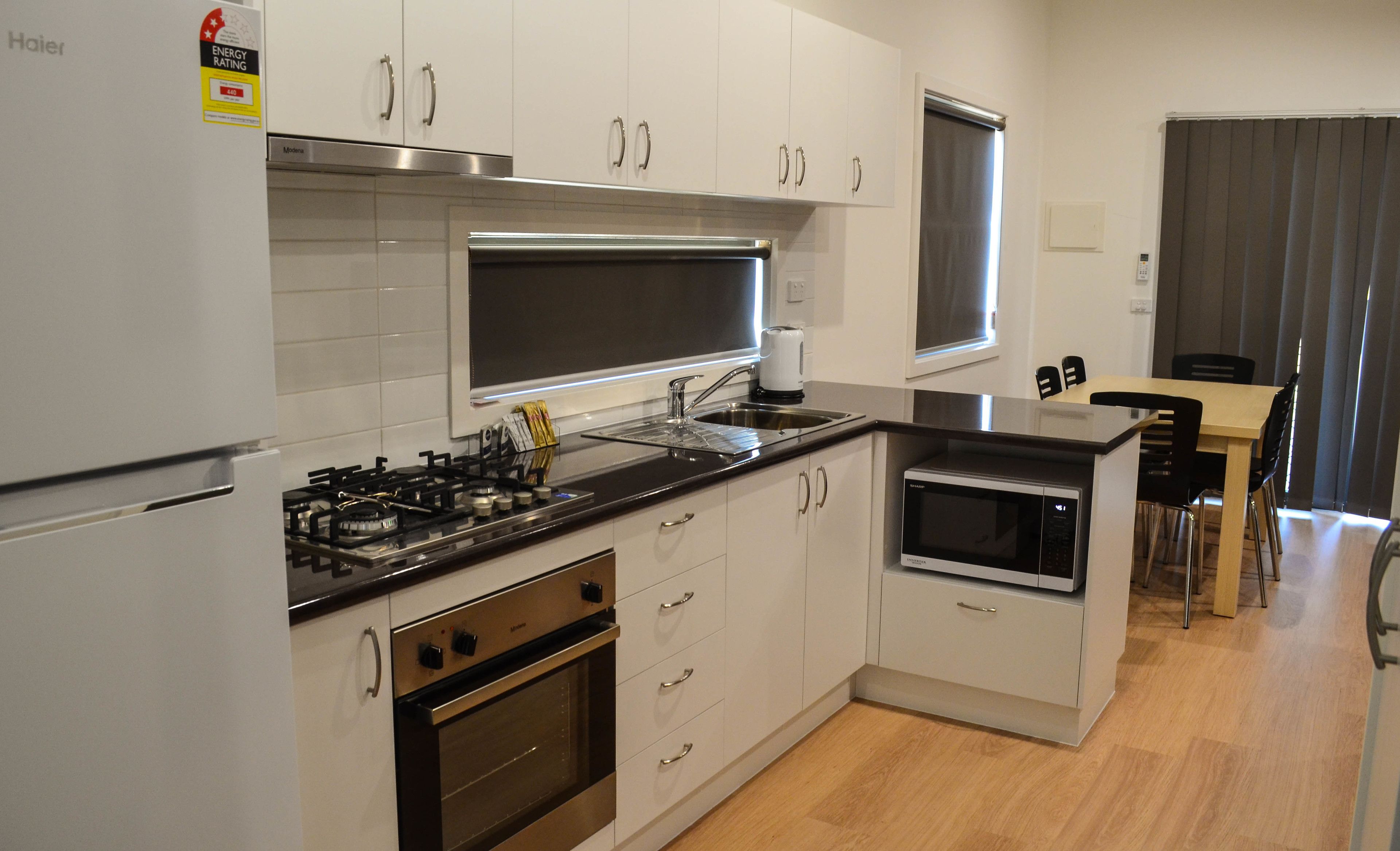 Een moderne keuken met witte kasten, roestvrijstalen apparatuur en een eethoek met houten meubels.
