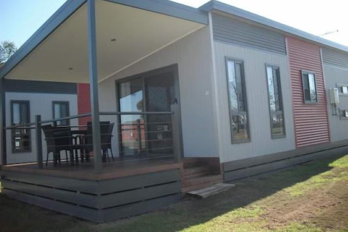 Uma casa móvel moderna com varanda coberta, janelas amplas e telhado plano.