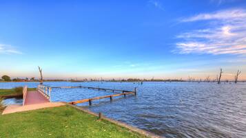 Une jetée en bois s’étendant sur une étendue d’eau calme, sous un ciel dégagé.