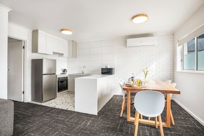 Una cocina moderna con una isla central, electrodomésticos de acero inoxidable y un comedor con mesa y sillas de madera.