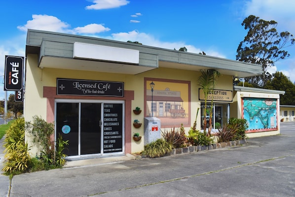 A building with a 'Licensed Café' sign, a 'Reception' sign, and a 'General Stores' sign.