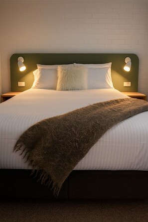 A neatly made bed with a white duvet, two white pillows, and a brown throw blanket. - Wilsons Promontory Motel (Foster)