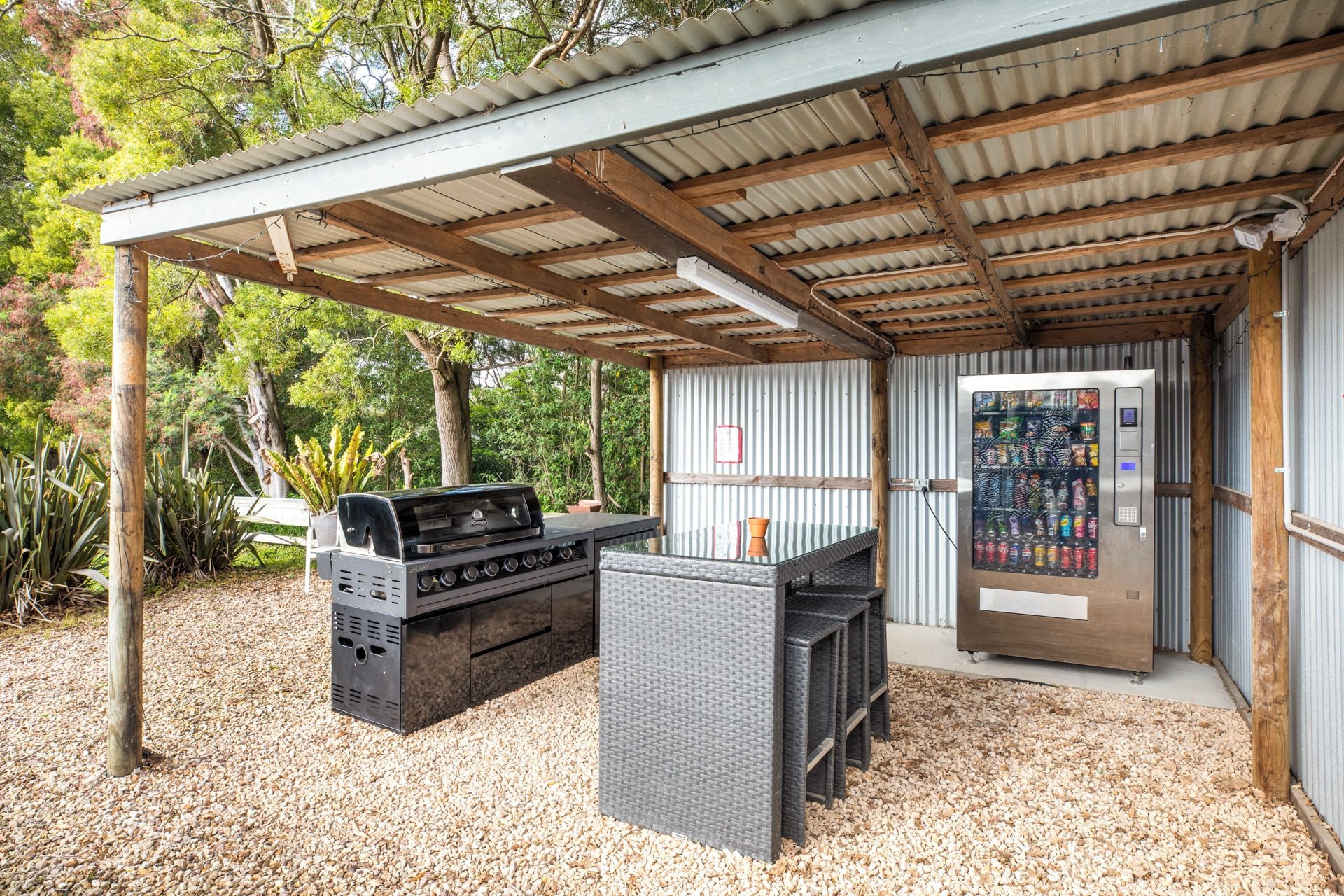 Un área de barbacoa al aire libre con una parrilla, asientos y una máquina expendedora.