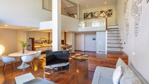A spacious living area with a dining table, sofa, and a staircase leading to an upper level. - Petitenget 501 (Keroboken Kelod)