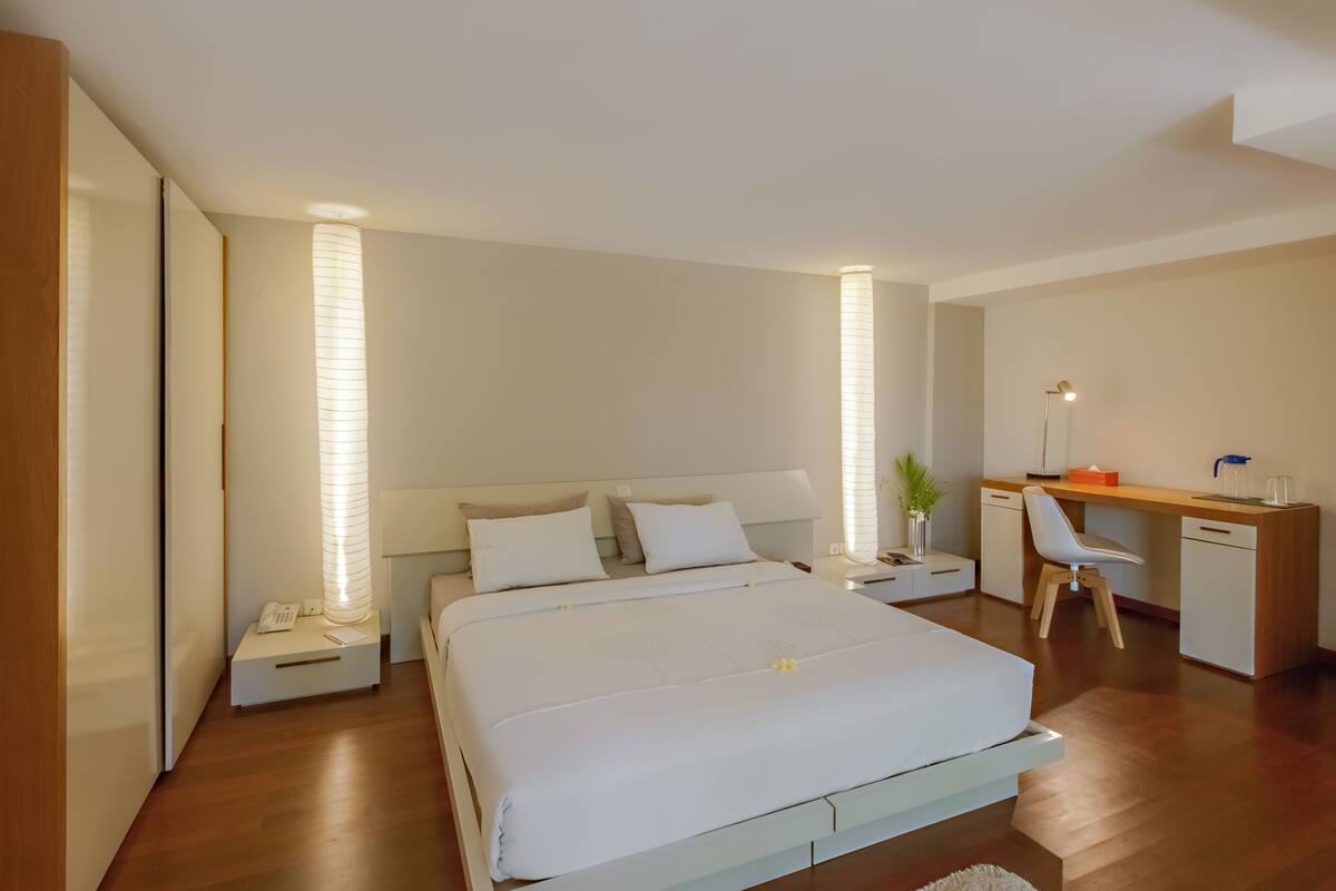 A modern bedroom with a bed, bedside tables, a desk, and a chair.