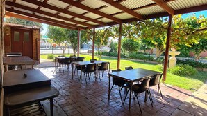 An outdoor patio with tables and chairs, a brick floor, and a covered area with a corrugated roof. - Wentworth Central Motor Inn (Wentworth)