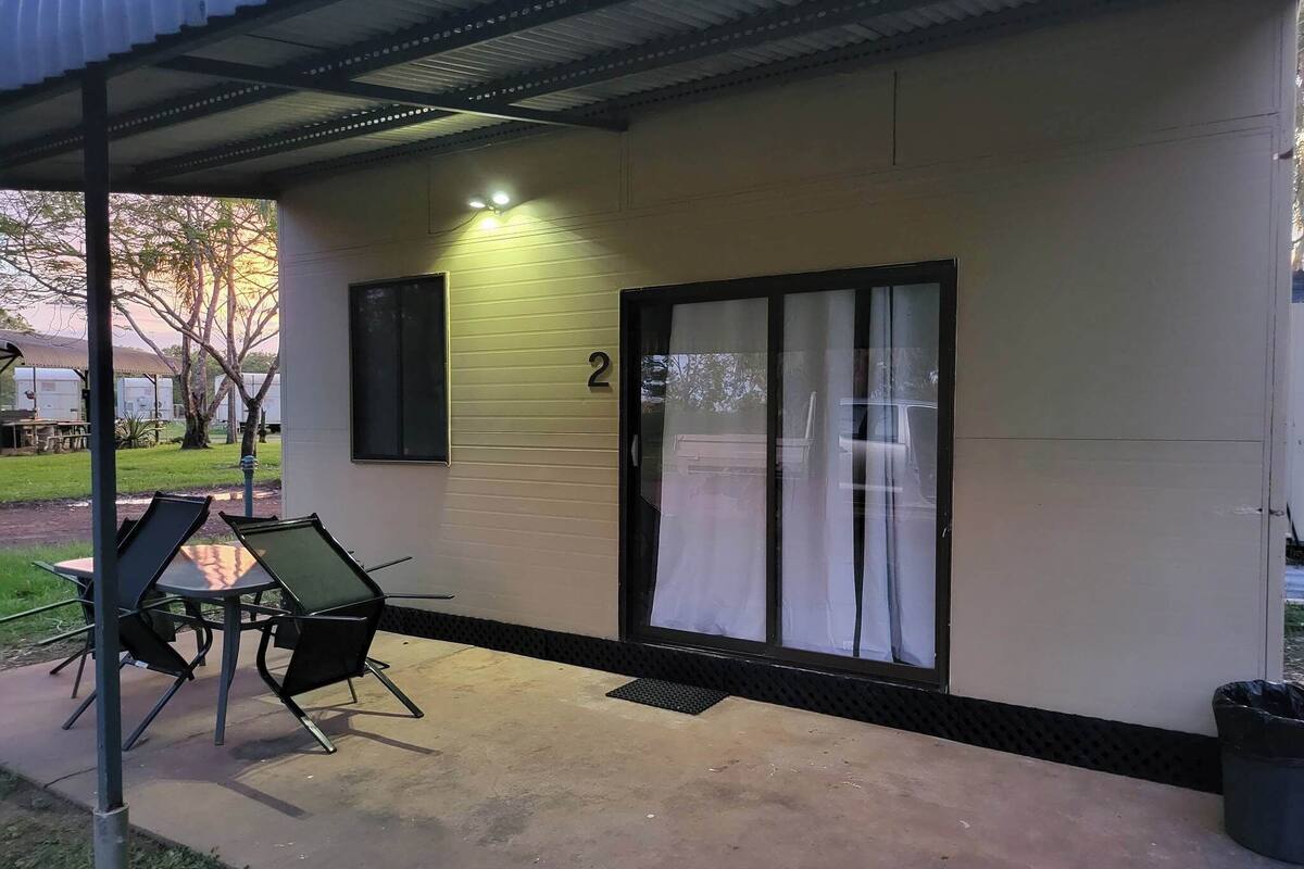 A building with a number '2' on the wall, a sliding glass door, and two chairs outside.