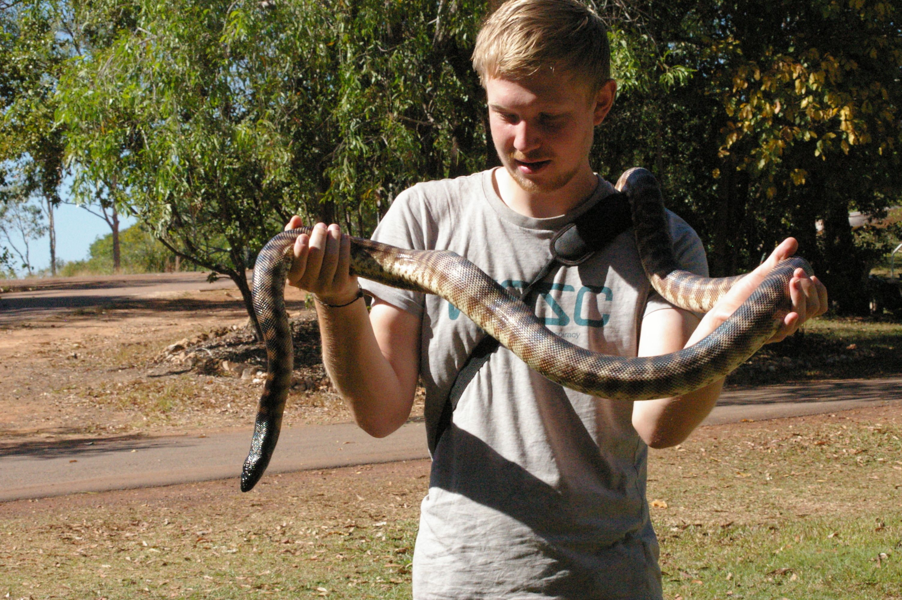 A person holding a large snake.