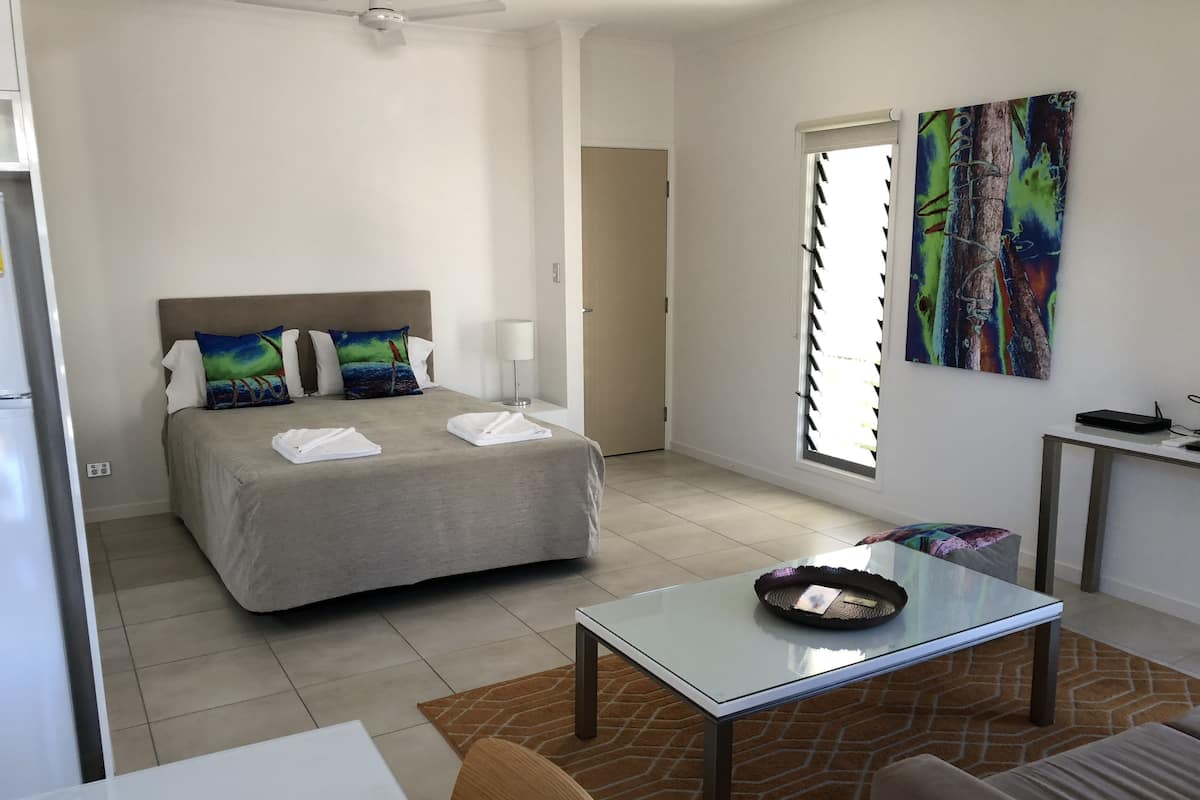 Une chambre d’hôtel avec un lit, un bureau, une chaise, une table et un tableau au mur.