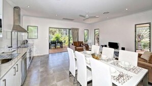A modern kitchen with a dining area, large windows, and a ceiling fan. - Woodgate Beach Houses (Woodgate)