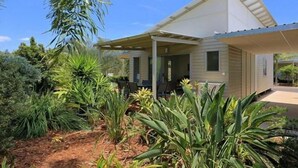 A modern house with a covered porch, surrounded by lush greenery. - Woodgate Beach Houses (Woodgate)