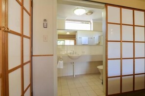A traditional Japanese-style bathroom with a sliding door, a sink, and a toilet.