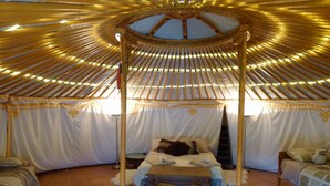 Una tradizionale yurta con un letto a baldacchino, un tavolino e due zone notte con panche.