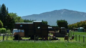 Un camper d'epoca parcheggiato in un prato erboso con una montagna sullo sfondo.