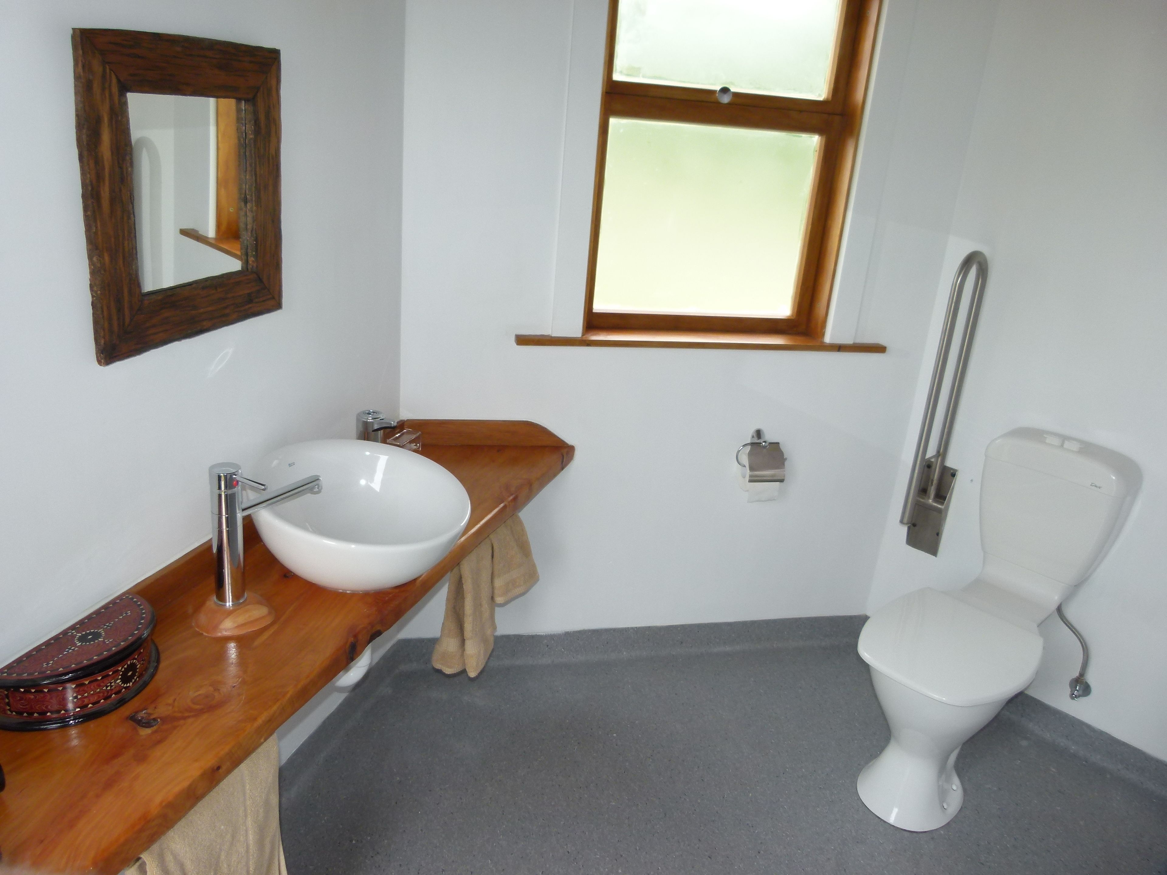 A bathroom with a wooden vanity, white sink, and a toilet.