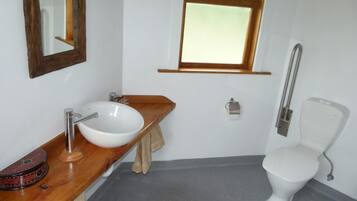 A bathroom with a wooden vanity, white sink, and a toilet.