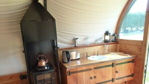 Una cucina compatta con un camino a legna, un lavello e una finestra.