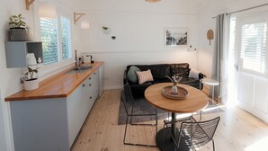 Cozinha moderna com bancada de madeira, pia e área de jantar com mesa redonda e cadeiras.