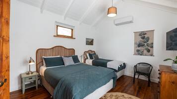 Ein Schlafzimmer mit zwei Betten, einem Nachttisch mit Lampe, einem Holzstuhl und einem kleinen Tisch mit Pflanze.