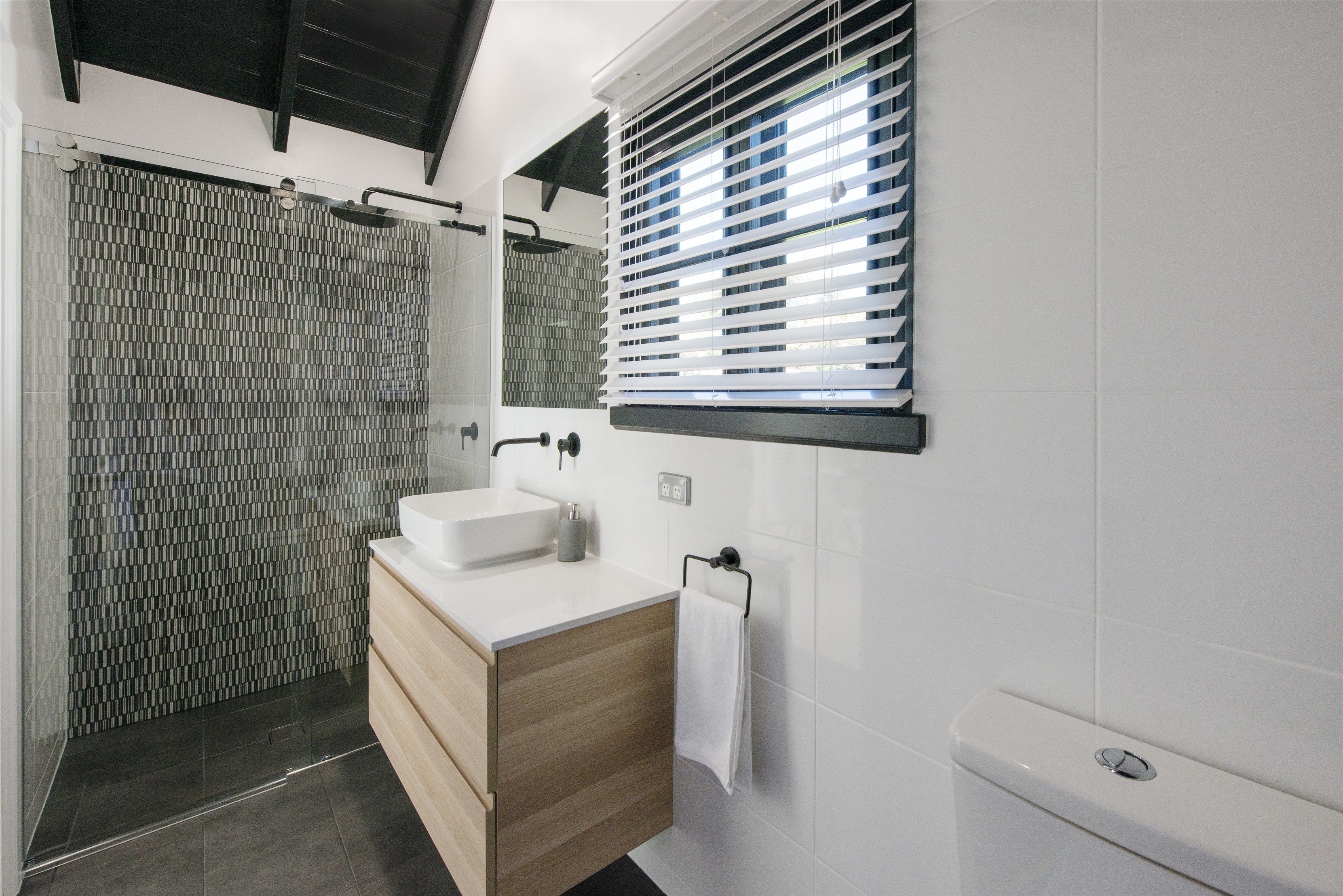 A modern bathroom with a shower, a sink, and a toilet.