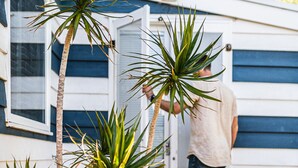 Uma pessoa abrindo uma porta para uma casa com revestimento azul e um deck de madeira.