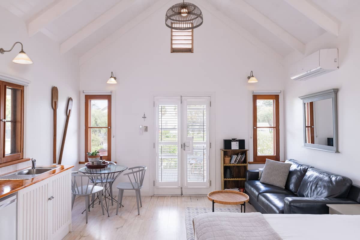 A spacious room with a kitchen, dining area, and a cozy seating area with a leather couch and a small round table.