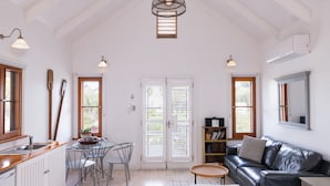 Um quarto espaçoso com cozinha, sala de jantar e um cantinho aconchegante com sofá de couro e uma mesa redonda pequena.