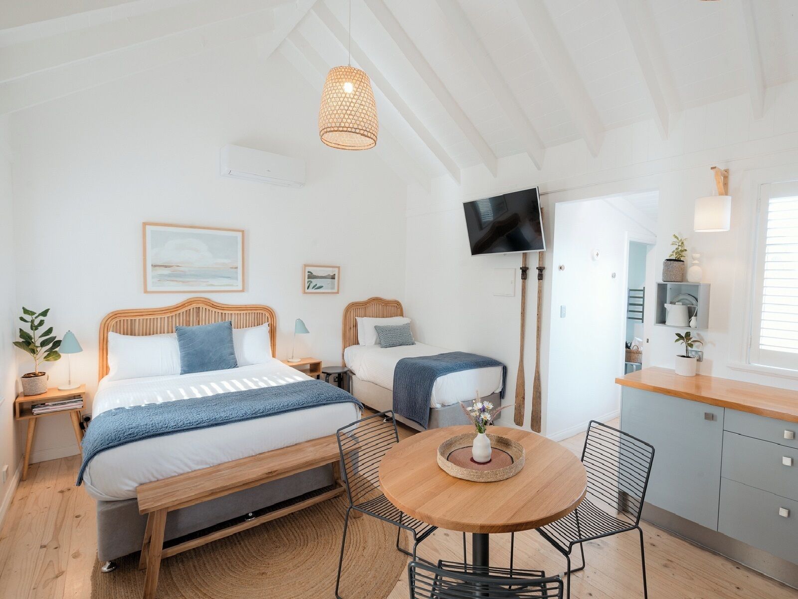 A modern bedroom with a bed, bedside tables, a TV, and a small dining area with chairs and a table.