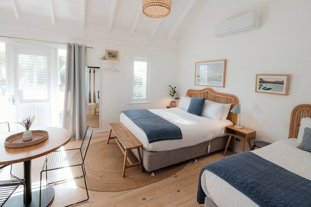 A bedroom with a bed, bedside tables, a desk, and a hanging light fixture.