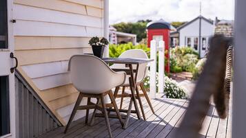 A wooden deck with a table and chairs, a potted plant, and a red mailbox in the background.