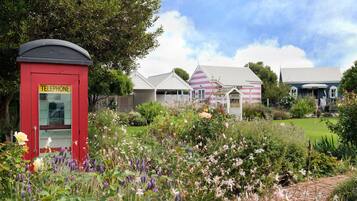 A traditional red telephone booth and a row of quaint, colorful houses with a well-maintained garden in the foreground.