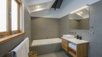 A modern bathroom with a bathtub, a vanity with a mirror, and a window.