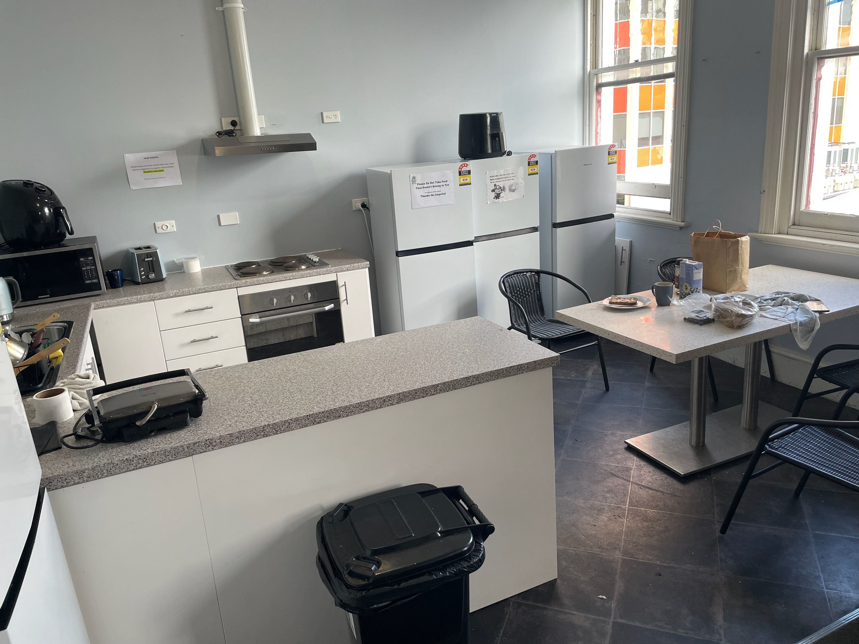 A compact kitchenette with a microwave, toaster, stove, and refrigerator. There is a small dining area with a table and chairs.