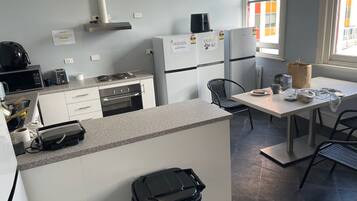 A compact kitchenette with a microwave, toaster, stove, and refrigerator. There is a small dining area with a table and chairs.