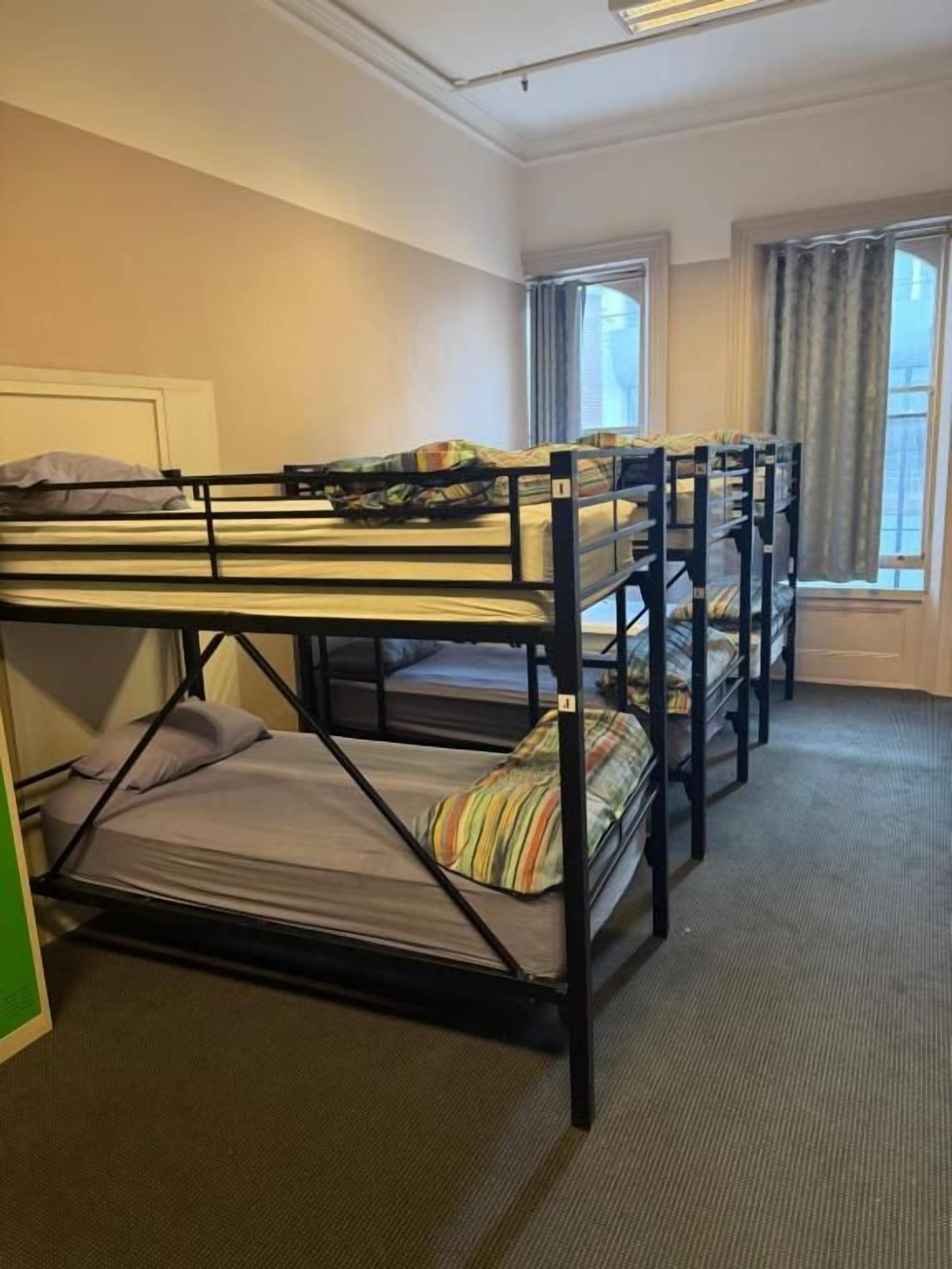 A room with bunk beds, a window with curtains, and a carpeted floor.