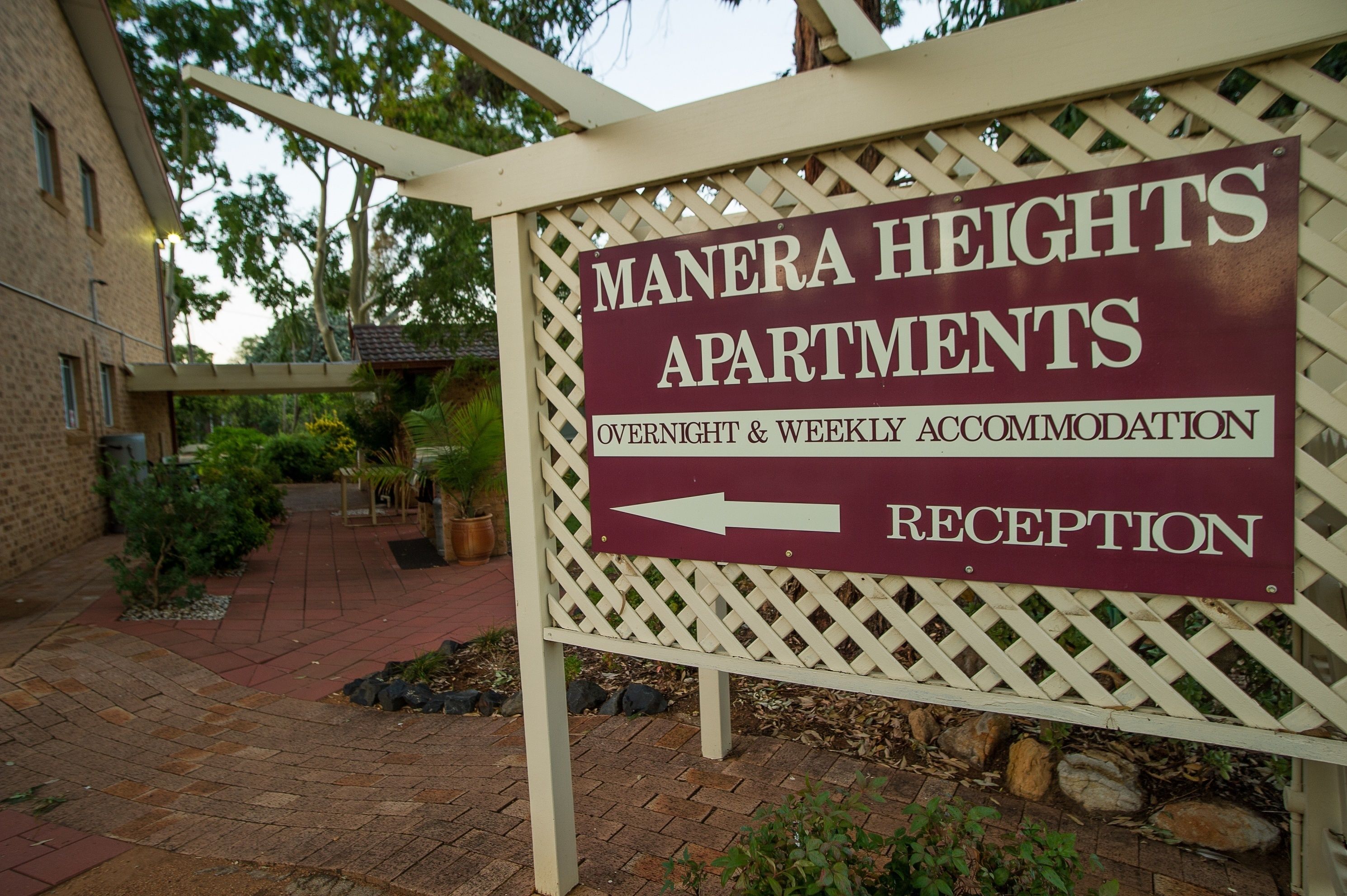 Señal de Apartamentos Manera Heights que indica alojamiento nocturno y semanal, con indicación de la dirección de la recepción.
