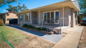 A single-story house with a covered patio, a small garden, and a paved driveway. - Manera Heights Apartment Motel (Dubbo)