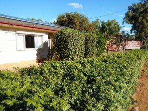 A residential area with a white house, a well-maintained hedge, and a sign for Manera Heights Apartments. - Manera Heights Apartment Motel (Dubbo)