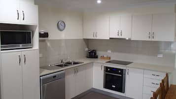 A modern kitchen with white cabinets, stainless steel appliances, and a clock on the wall.