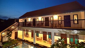 A two-story building with a balcony, outdoor seating area, and a swimming pool. - Sanur Guest House (Denpasar)