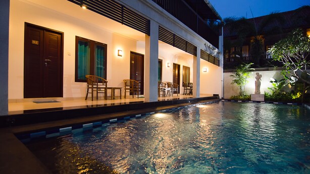 A hotel with a swimming pool, outdoor seating, and a statue. - Sanur Guest House (Denpasar)