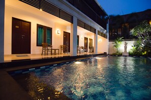 A hotel with a swimming pool, outdoor seating, and a statue. - Sanur Guest House (Denpasar)